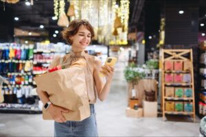 Woman uses her phone in a grocery store because of a cell phone signal booster for retail.